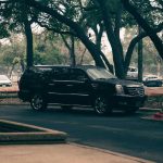 Une SUV noire circule sur une route bordée d'arbres