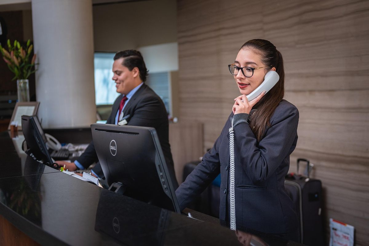 Une femme parle au téléphone, un homme travaille au bureau d'accueil
