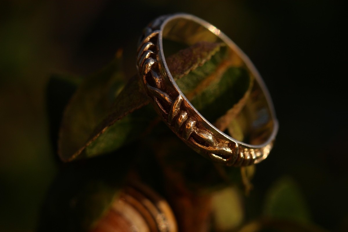 Bracelet doré sur feuille, lumière naturelle, arrière-plan sombre